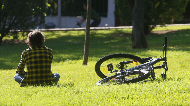 Un hombre descansa sobre el césped junto a su bicicleta.