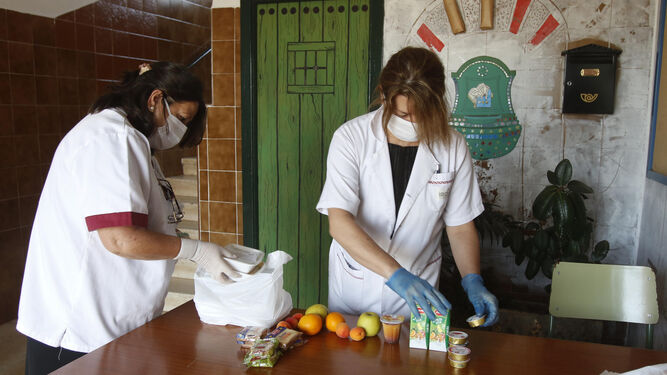 Dos operarias preparan los alimentos para los niños en un colegio.