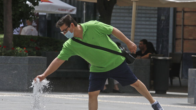 Un hombre con mascarilla se refresca en la plaza de las Tendillas de Córdoba.