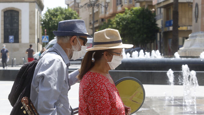Dos personas pasean por la plaza de las Tendillas protegidas con mascarillas.