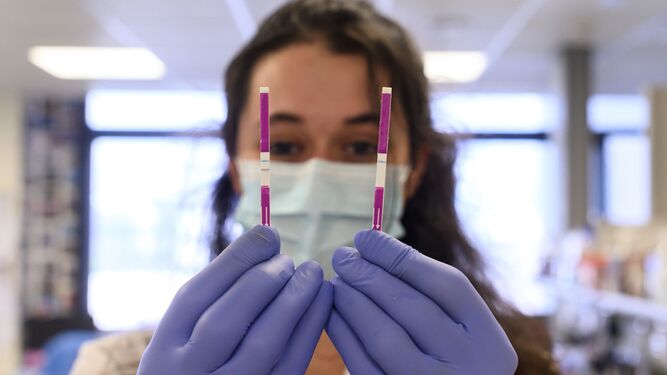 Una investigadora muestra los resultados de dos test de coronavirus.