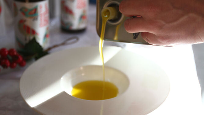 Una persona echa aceite de oliva en un plato para degustar.
