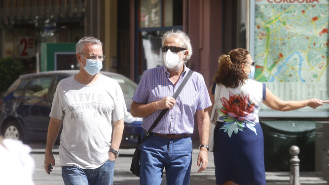 Varias personas pasean con mascarilla por Córdoba.