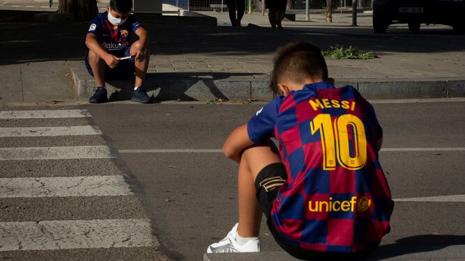 Dos jóvenes aficionados esperan a la entrada de la ciudad deportiva Joan Gamper la llegada de los jugadores  del Barcelona para realizarse las pruebas PCR.