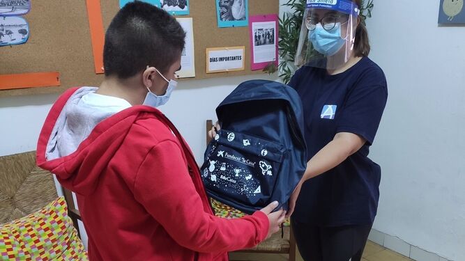 Una voluntaria entrega el kit de material escolar a un niño.