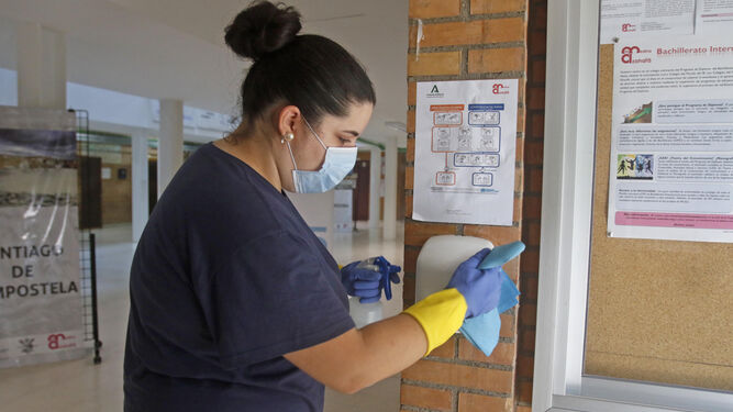 Una trabajadora del servicio de limpieza desinfecta un dispensador en el colegio Medina Azahara.