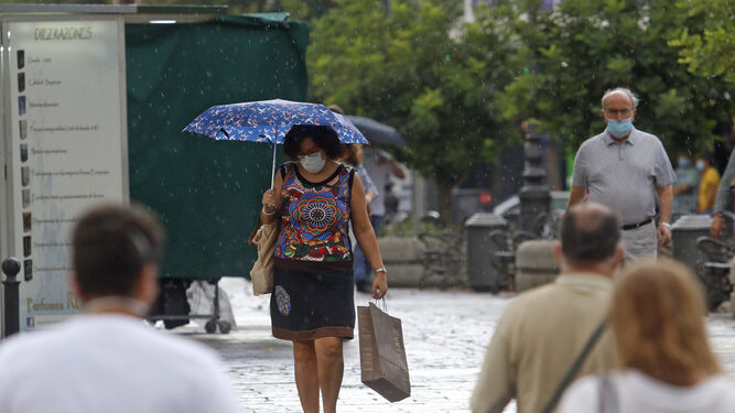 Varias personas caminan por el centro de Córdoba bajo la lluvia.