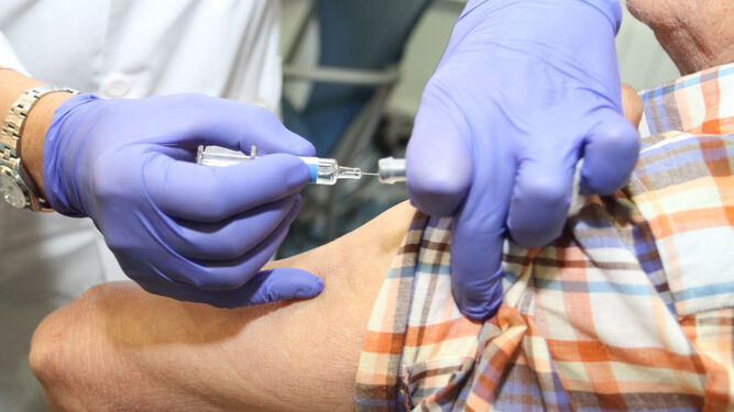 Una enfermera inyecta una vacuna de la gripe a un paciente.