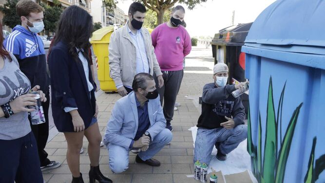 Cintia Bustos, David Dorado y Salvador García observan la realización de un grafiti en un contenedor.