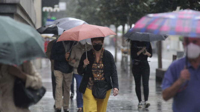 Con paraguas y mascarilla por el centro de Córdoba.