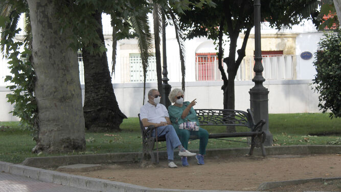 Una pareja con mascarilla, sentada en un banco en Córdoba.