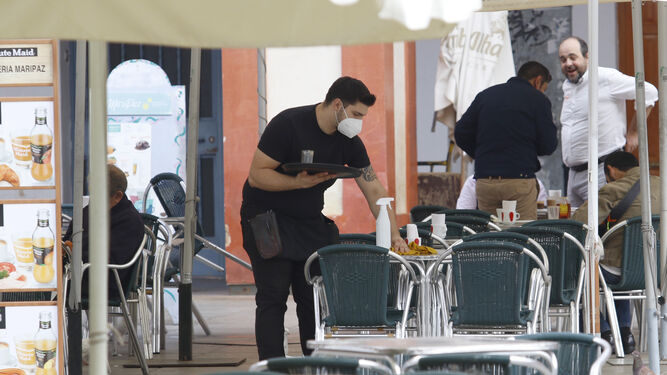 Un camarero limpia la mesa de una terraza en la plaza de la Corredera.