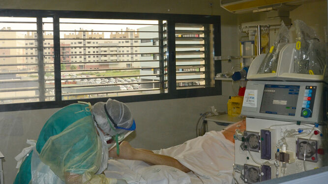 Una profesional sanitaria observa a un paciente de la UCI del Reina Sofía.