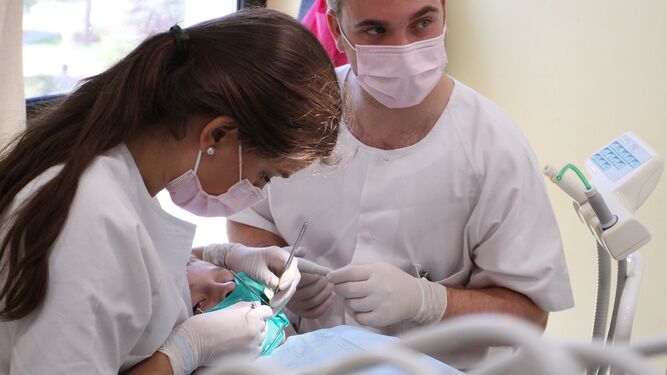 Dos dentistas atienden a un paciente.