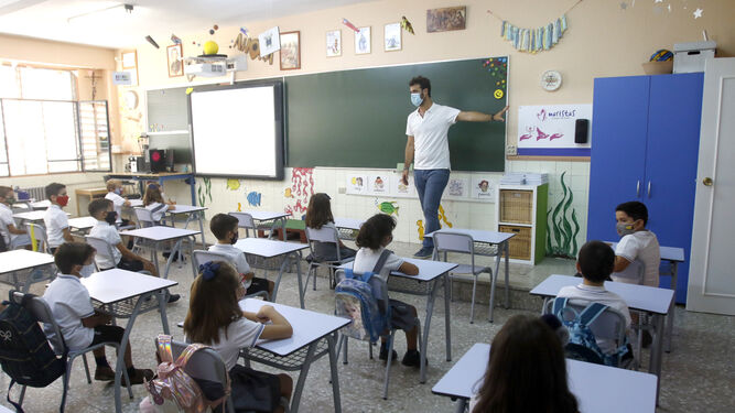 Una maestro imparte clases a alumnos de Primaria en un aula donde todos llevan mascarillas.