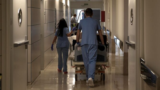 Dos profesionales sanitarios llevan una camilla por el pasillo de un hospital.