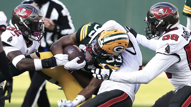Varios jugadores de los Buccaneers bloquean a un rival de los Packers