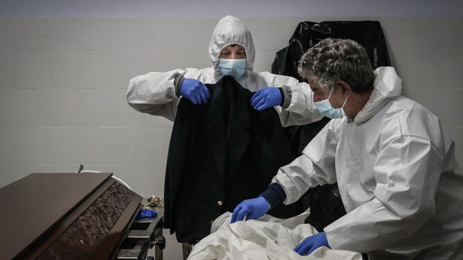 Dos trabajadores de una funeraria preparan a una víctima del covid en la localidad portuguesa de Amadora.