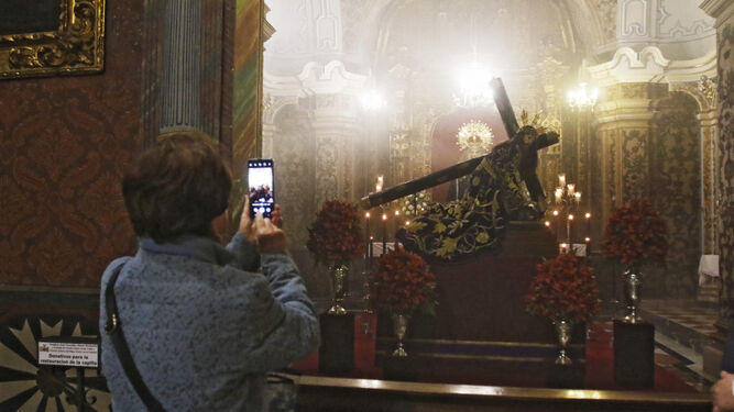 Una mujer toma una imagen de El Caído expuesto en veneración.