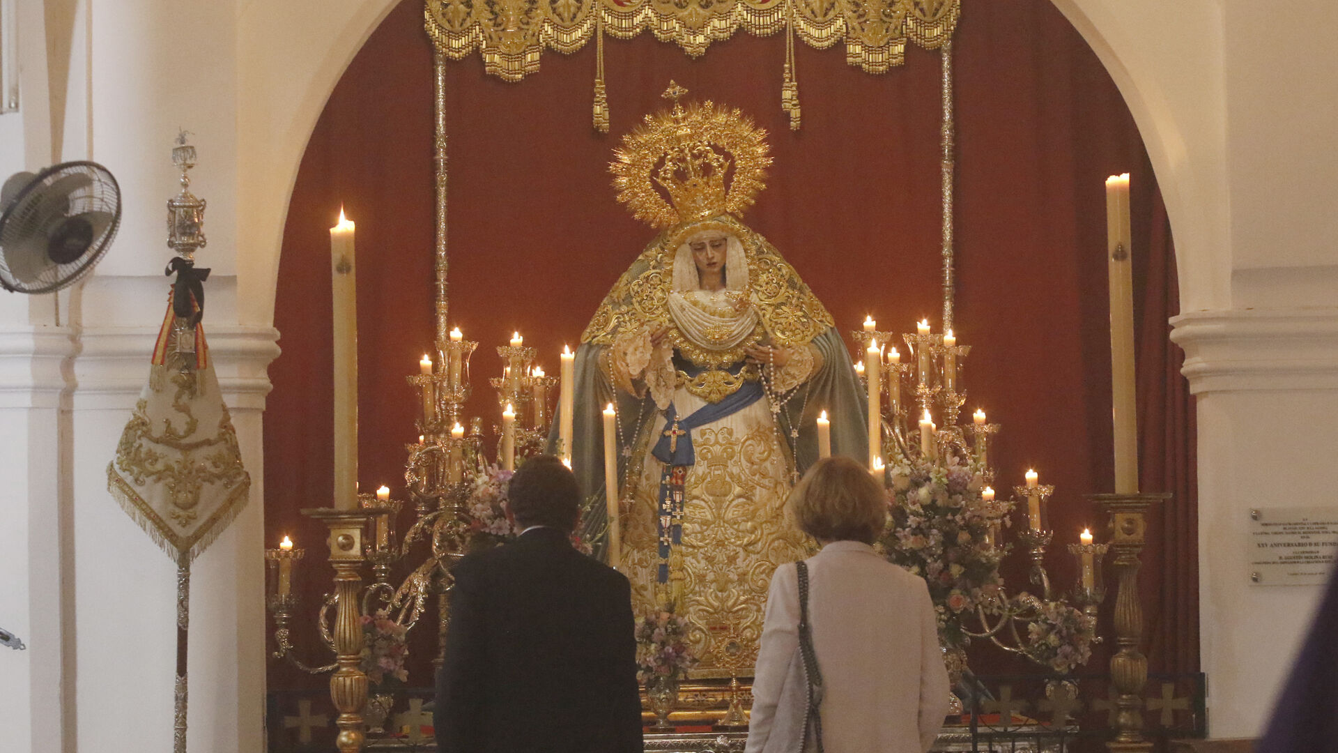 Dos personas observan a la Virgen de la Salud de la hermandad de la Agon&iacute;a.