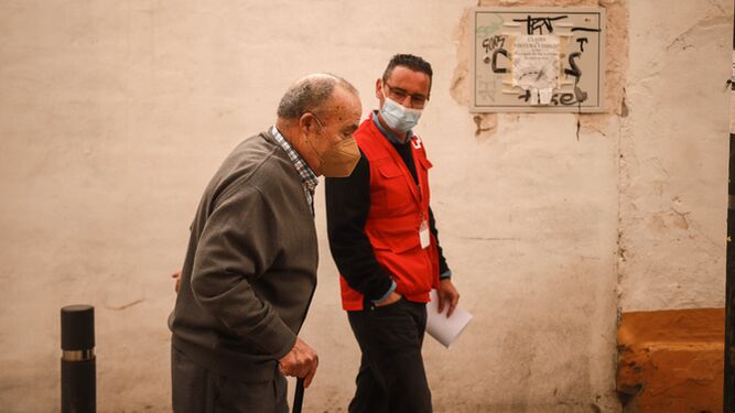Un voluntario de Cruz Roja acompaña a una persona mayor a vacunarse.