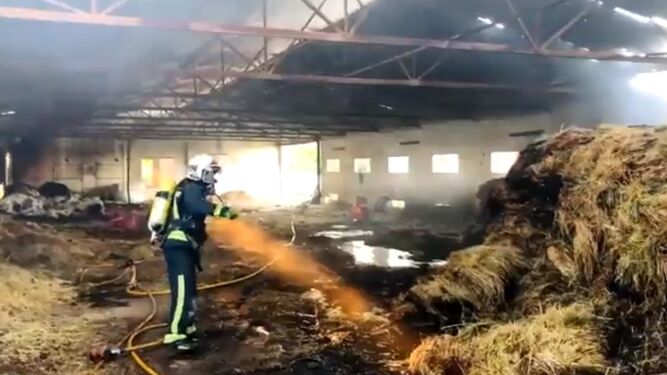 Un bombero extingue el fuego en una nave agrícola de Fontanar de Quintos.