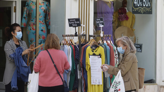 Una dependienta atiende a varias clientas en su tienda en Córdoba.