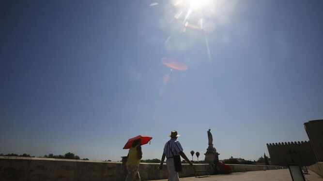 Dos personas atraviesan el Puente Romano de Córdoba.