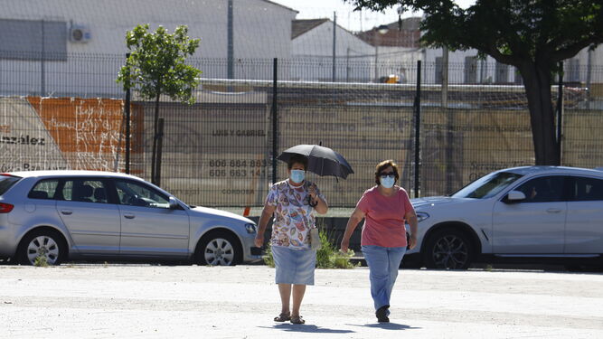 Dos mujeres caminan protegiéndose del sol.
