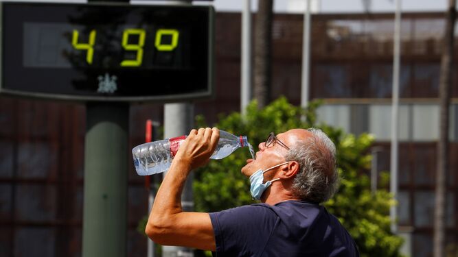 Un hombre bebe agua de una botella en Córdoba mientras el termómetro marca 49 grados.