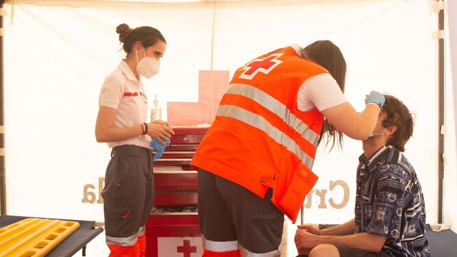 Personal sanitario de Cruz Roja atiende a un paciente en una carpa.