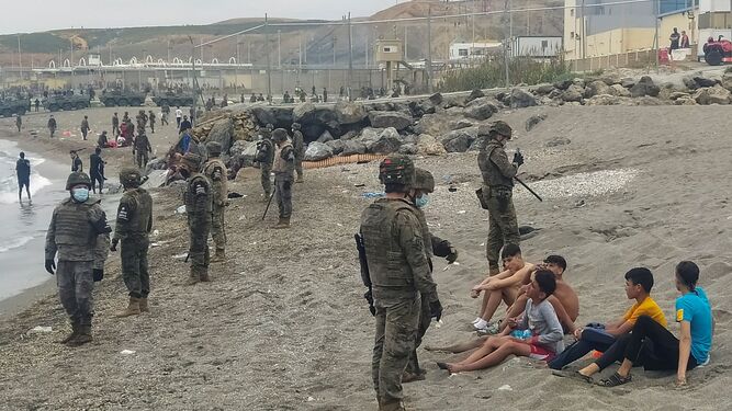 Miembros del Ejército observan a un grupo de los inmigrantes que llegaron en mayo a los espigones fronterizos de Ceuta.