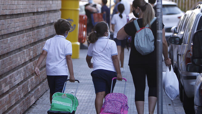 Dos niños junto a su madre, camino del colegio.
