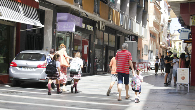Padres y abuelos caminan con los niños por las calles del centro en la vuelta al cole de 2020.