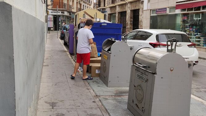 Un joven deposita basura en un contenedor.