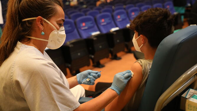 Una sanitaria vacuna a un joven.