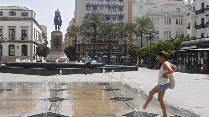 Una joven se refresca los pies en la plaza de Las Tendillas.
