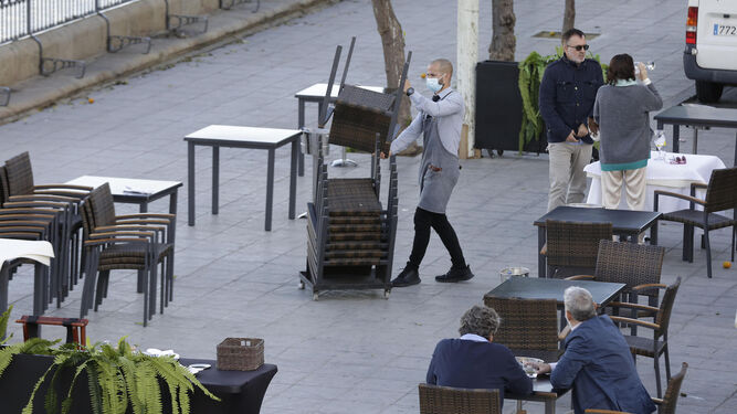 Un trabajador del sector de la hostelería desmonta una terraza.