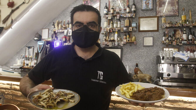 El hostelero Óscar Ruiz sujeta varios platos de comida típica de Otoño de la Taberna Góngora.
