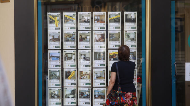 Una mujer mira varios carteles de una inmobiliaria.