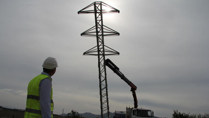 Un trabajador de Endesa  frente a una torre eléctrica.