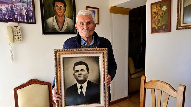 Pepe Alarcón García, de 90 años, fotografiado con el retrato de su padre en su casa.