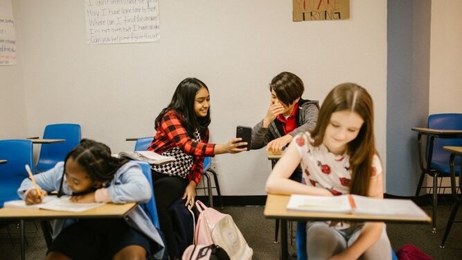 Un grupo de alumnos mira el móvil en clase.