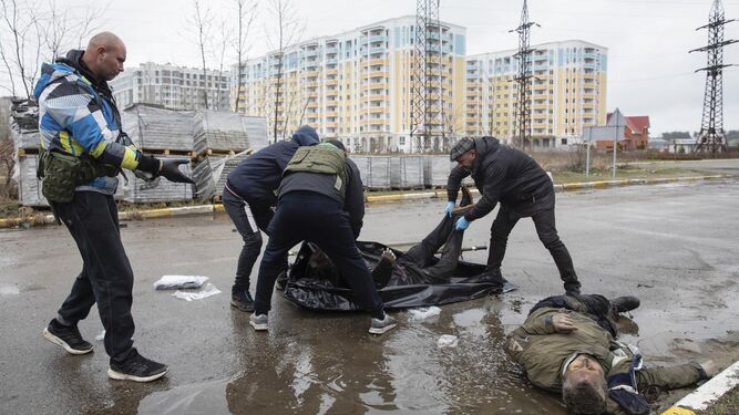 Varias personas retiran el cuerpo sin vida de un civil de una calle de Bucha, Ucrania.