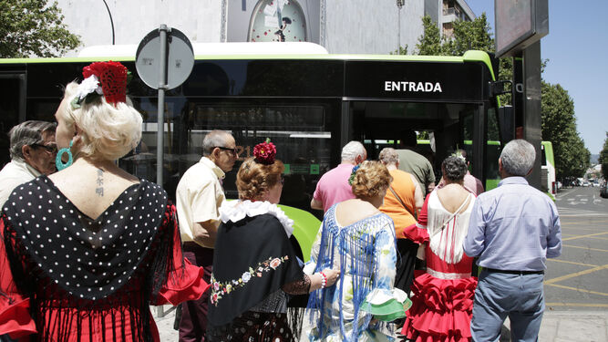 Mujeres con trajes de flamenca se suben a un autobús.