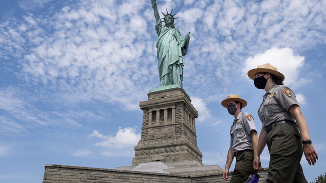 Dos 'rangers' de la Guardia Nacional de EEUU pasan con mascarillas ante la Estatua de la Libertad.