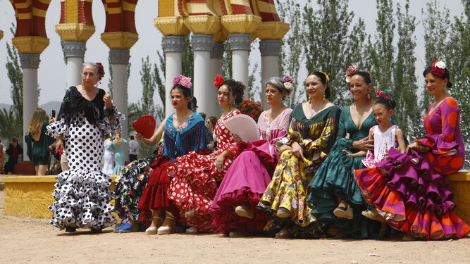 Un grupo de mujeres, vestidas de flamenca, se toman un respiro junto a la portada.