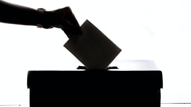 Una persona deposita su voto en una urna.