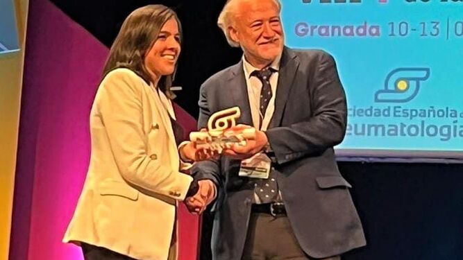 Laura Bautista recoge el premio de manos del presidente de la Sociedad Española de Reumatología, José María Álvaro Gracia.