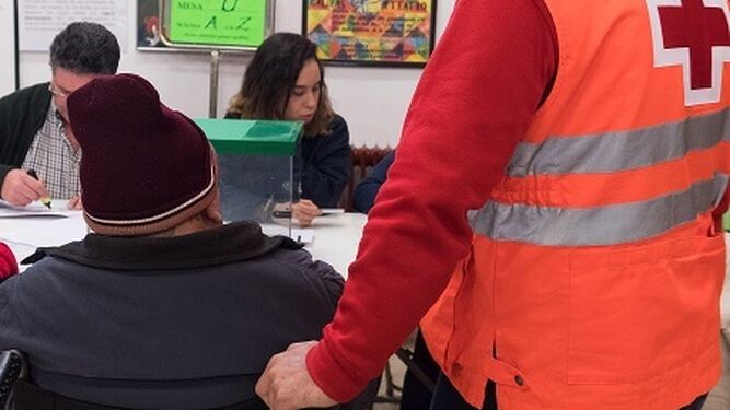 Un voluntario de Cruz Roja acompaña a una persona a votar.